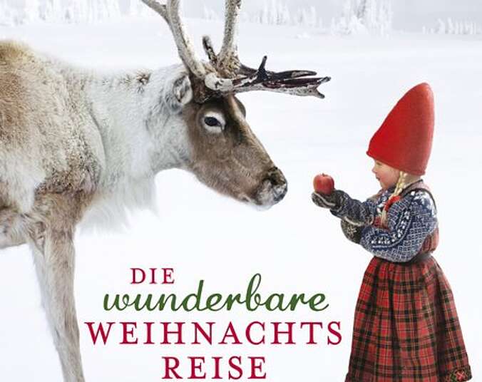 Anja steht mit einem Apfel in der Hand vor einem Rentier.