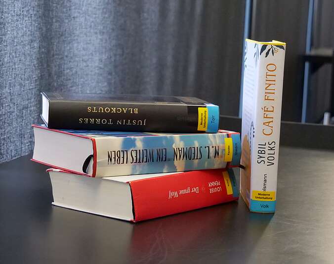 Ein kleiner Bücherstapel auf einem schwarzen Tisch.