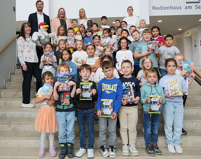 Viele Kinder mit Büchern stehen auf einer Treppe