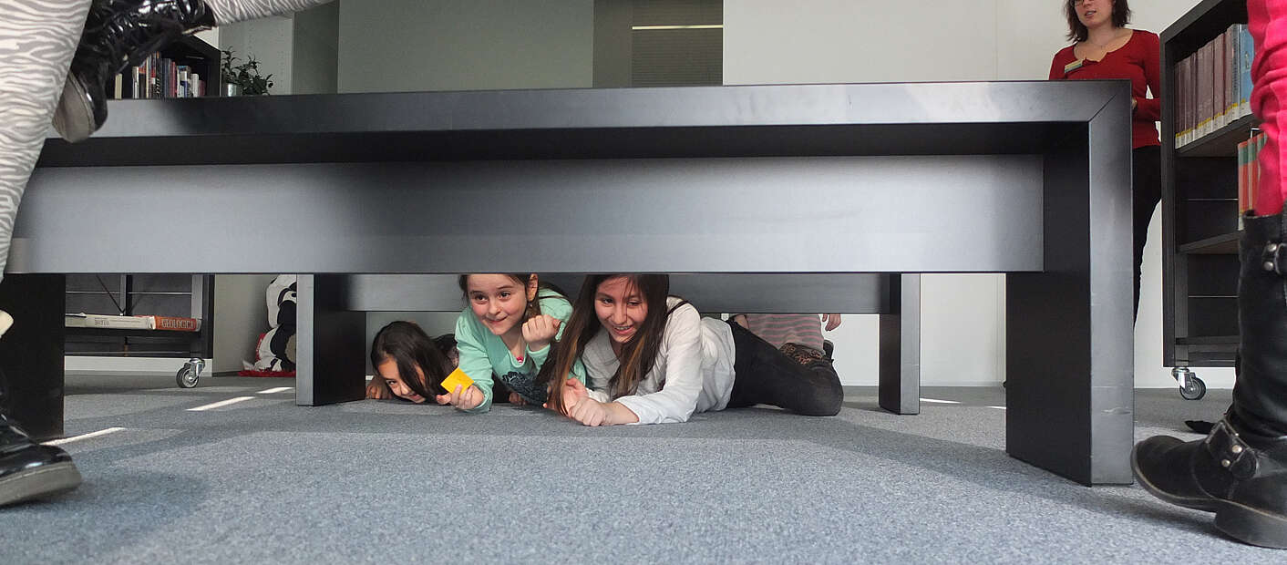 Zwei Kinder liegen unter einem Tisch