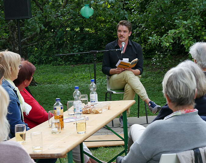 Ein Mann liest Menschen im Garten vor