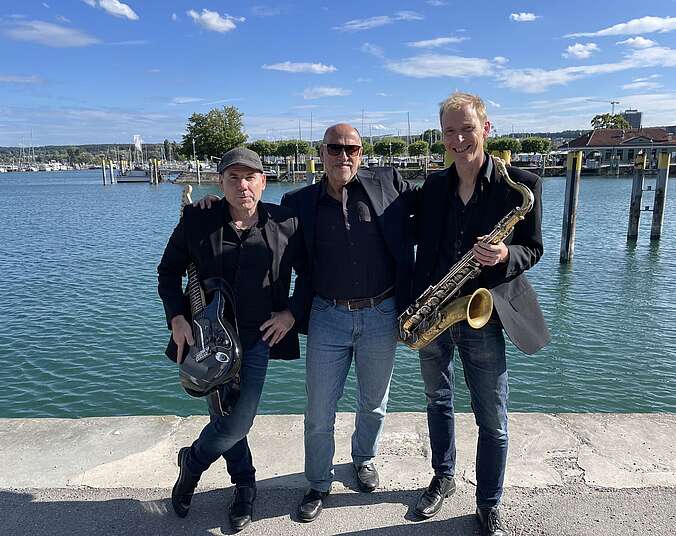 Drei Männer mit Instrumenten am Hafen