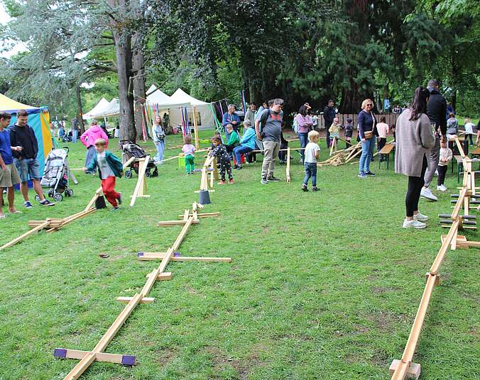 Menschen auf Wiese mit Murmelbahn