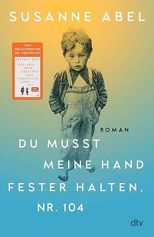 Ein kleiner Junge in Latzhosen steht allein mit den Händen in den Hosentaschen da.